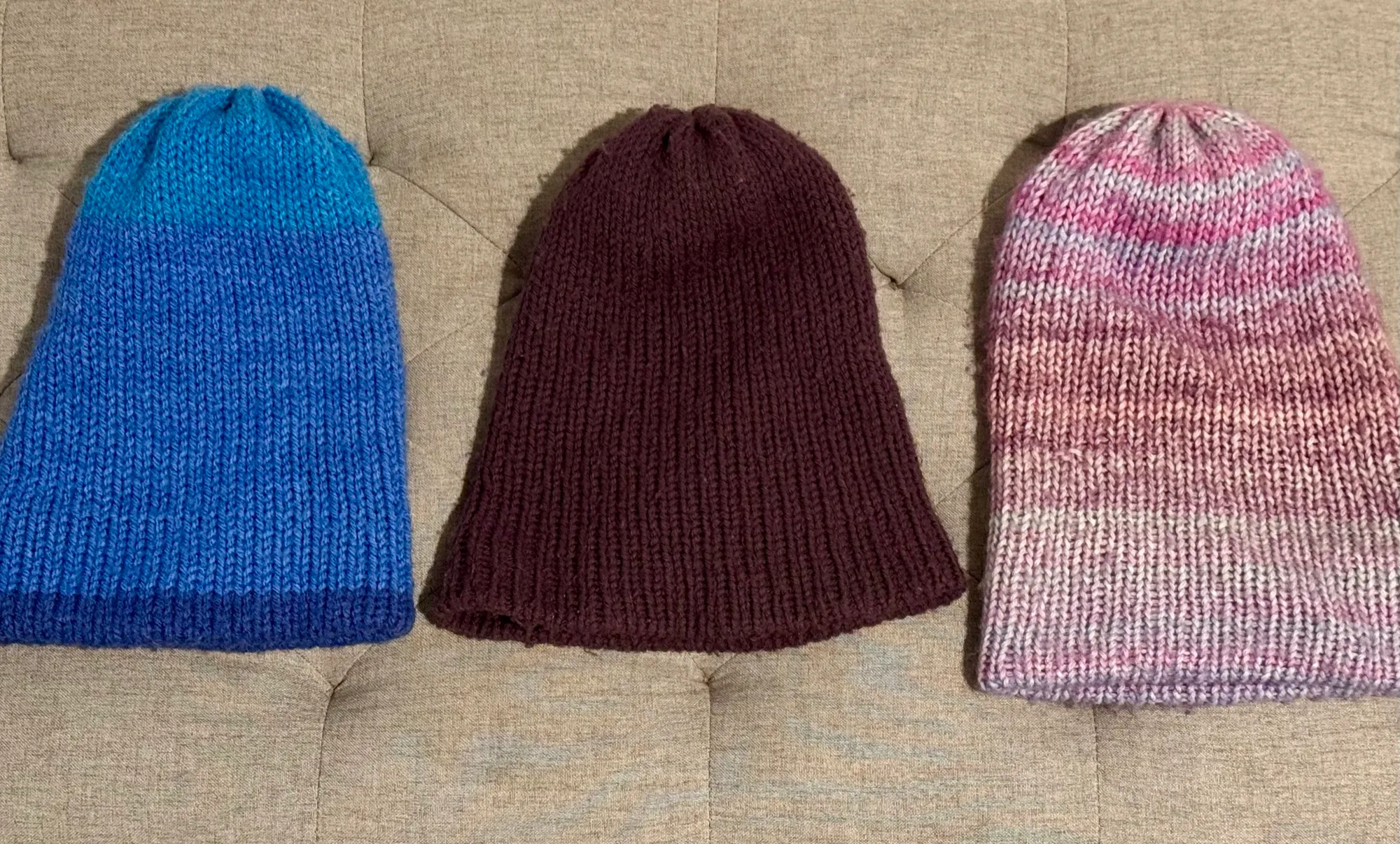 Three more hand-knit beanies: an ocean-blue gradient hat, a deep plum hat, and a pink and lilac variegated hat.